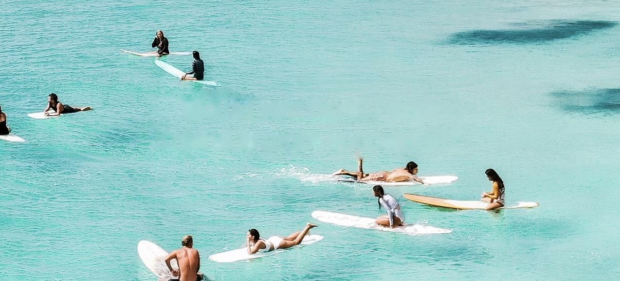 Surfers waiting on longboards in a turquoise bay